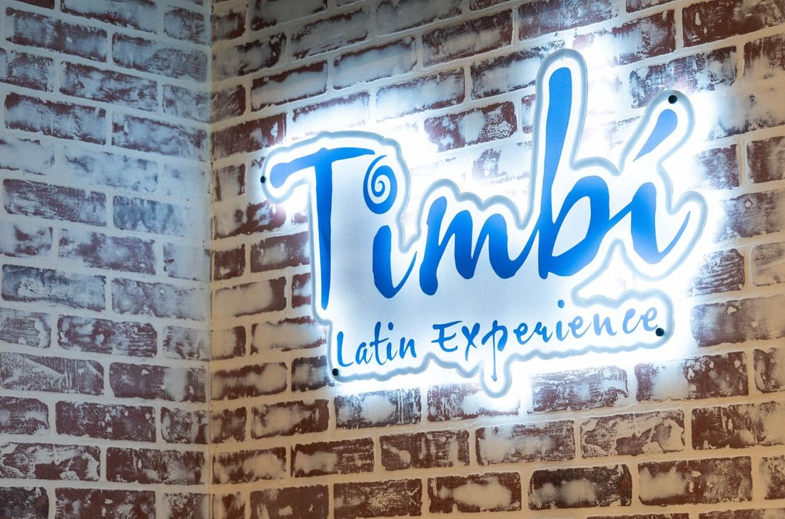 Timbí neon sign on whitewashed brick